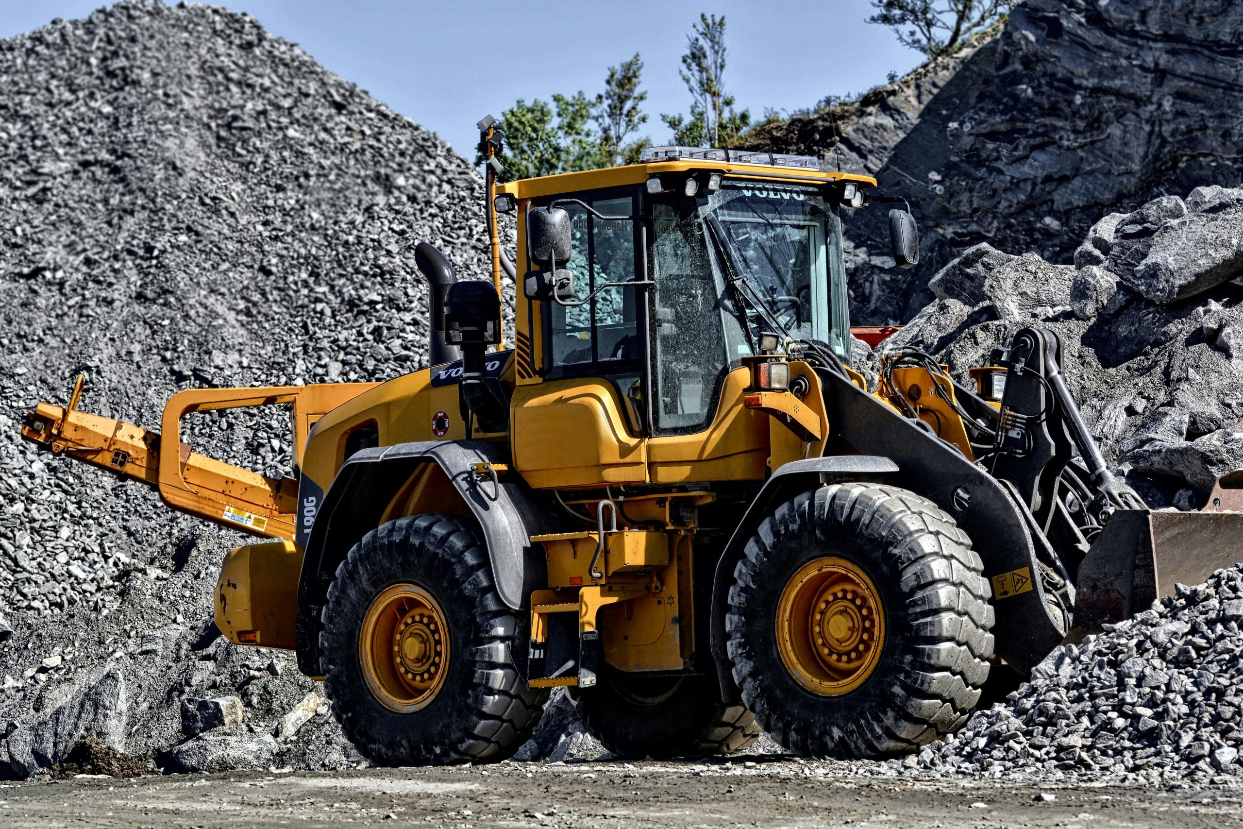 Powerful yellow construction loader moving gravel in an industrial quarry site.