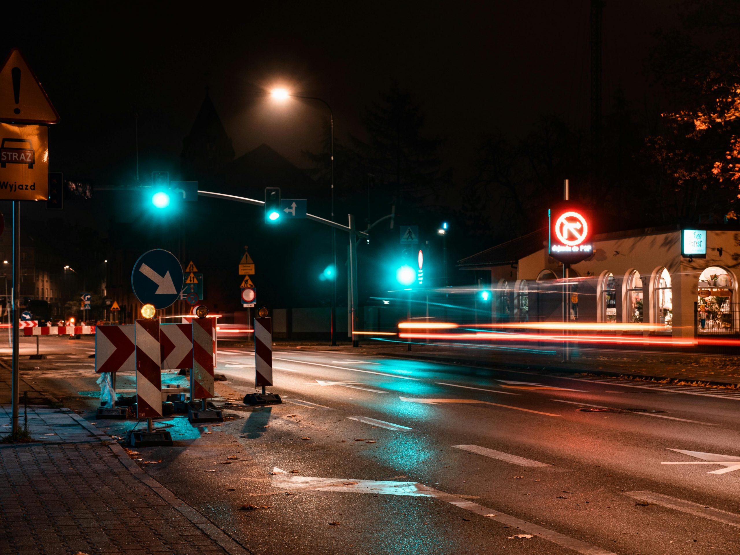 Nighttime city intersection with traffic and illuminated street signs.